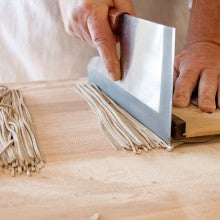 Slicing homemade noodles on a counter