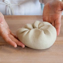 A ball of noodle dough on a wooden counter