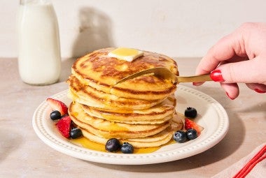 Easy Buttermilk Pancakes topped with maple syrup on a plate with fresh fruit