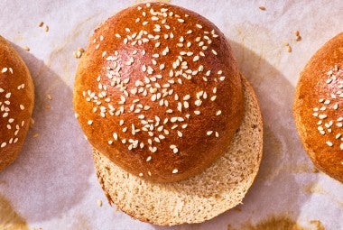 100% Whole Wheat Hamburger Buns sliced and on parchment paper