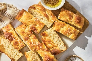 Sourdough Focaccia sliced on a cutting board with a dish of olive oil