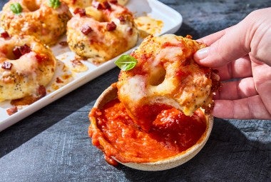 Dipping a mini pizza bagel into a small bowl of marina.