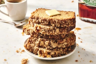 Five slices of Pancake Bread stacked on a plate showing a crumbly exterior and topped with butter.
