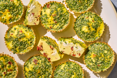 Egg Bites seen from the top showing greens and a cross-section of one with quiche like interior and cottage cheese within.