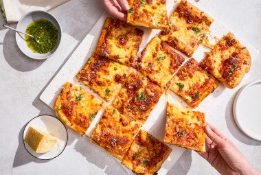 A sliced up Flaky Puff Crust Pizza with pieces being taken out