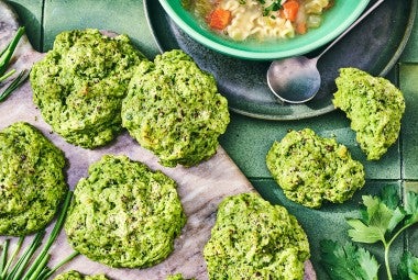 Green Goddess Herb Biscuits on cutting board with a bowl of soup in the frame.
