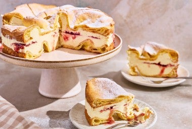 Karpatka Cake on a cake stand with slices on plates.