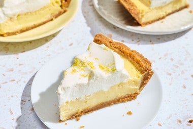 A slice of Lemon Cream Pie on a white plate.