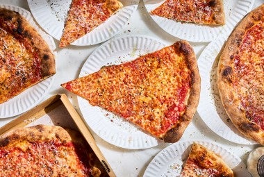 Slices of New York-Style Pizza paper plates arranged on a table seen from above.