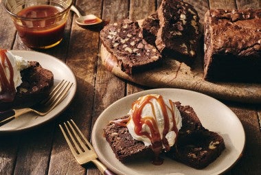 A sliced Brownie Loaf on a plate with vanilla ice cream and a caramel swirl