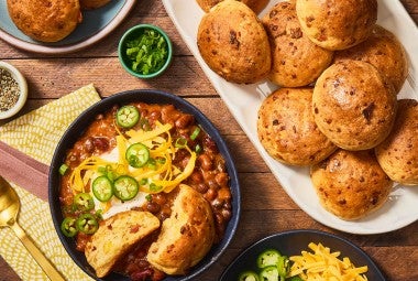 Gluten-Free Bacon Cheddar Rolls on a platter with a bowl of chili next to it. Seen from above.