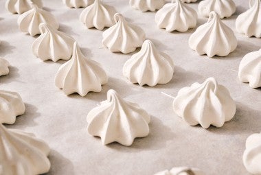 Meringue Kisses in neat rows on a counter.