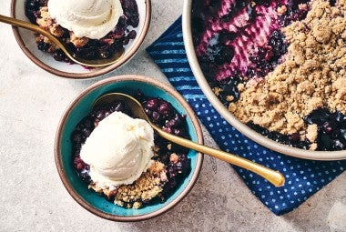 Blueberry Crisp in a round King Arthur Baking pie tin and also in a bowl topped with ice cream
