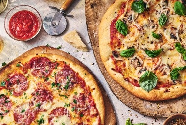 Two pizzas seen from above on wooden pizza peels