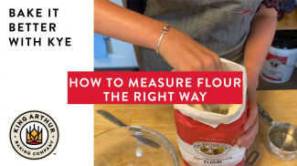 Hands measuring King Arthur flour from bag 