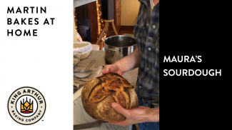 Hands holding baked sourdough loaf
